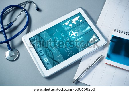 White tablet pc and doctor tools on gray surface Royalty-Free Stock Photo #530668258