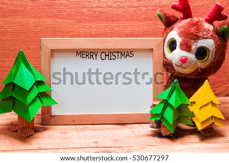 Blank whiteboard for your text on wooden background with Christmas tree, gift box and Teddy reindeer decoration image for Christmas holiday concept.