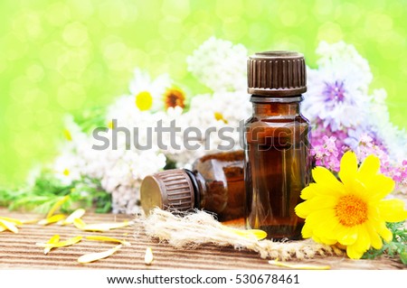 Essential oils on medicinal flowers and herbs background: chamomile, clover, calendula, yarrow, selective focus