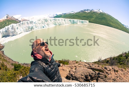 Young man solo traveler taking selfie at Perito Moreno glaciar in south american argentinian Patagonia - Adventure wanderlust concept on world famous nature wonder in Argentina - Warm turquoise filter