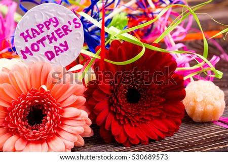 Flowers near Mother`s day card. Candy and colorful streamer. Bright gift for mommy. Attention and grattitute on holiday.