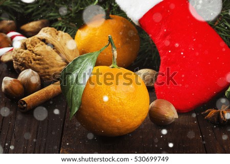 Gift in Christmas sock - tangerine, candy, nuts, cinnamon on a dark wooden background. Toning
