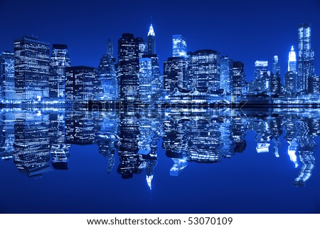Lower Manhattan in New York City at night with reflection in water with blue hue