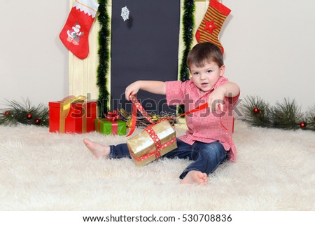 Little boy opening a Christmas present. Kid opening New Year gifts