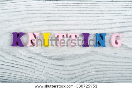 Knitting. Knitted Fabric Texture. Word composed from ABC alphabet letters on wooden background.