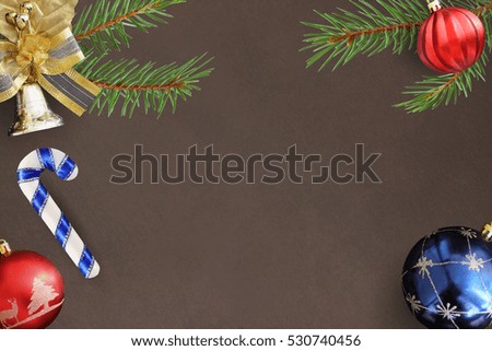 Christmas fir branch, stick, red wavy and blue balls and decorative bell on dark background