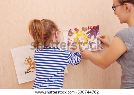 Mom and daughter are trying to hang a picture on the wall