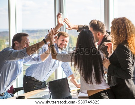 Business people showing team work and giving five after signing agreement or contract between companies, enterprises in office interior. Agreement or contract concept.