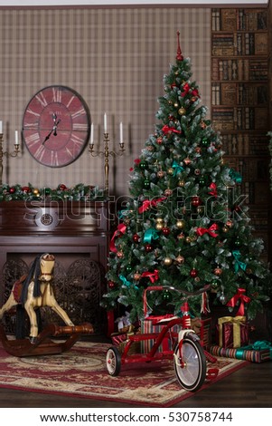 Big wonderful fairy Christmas tree in classical living room. Toys and gifts near the tree .