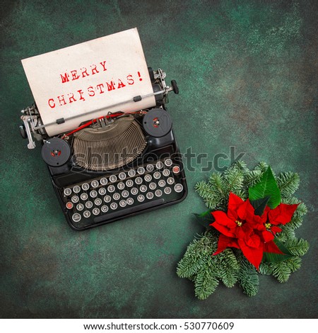 Vintage typewriter with Christmas decoration and red poinsettia flowers. Merry Christmas! Vintage style toned picture