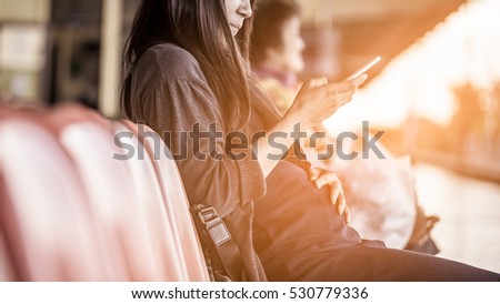 A pregnant playing smart phone on the chair in the train station. Selected focus at her hand. Royalty-Free Stock Photo #530779336