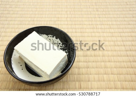 Tofu bean curd on black round plate placed on tatami rice straw flooring mat
