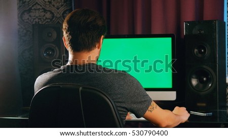 Working late. Confident young man  on his laptop PC with chroma key green screen while sitting at   place  night time. Handsome freelancer workspace. Creative manager  work.