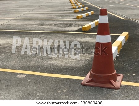 Traffic cone and empty parking car, text is parking on skin