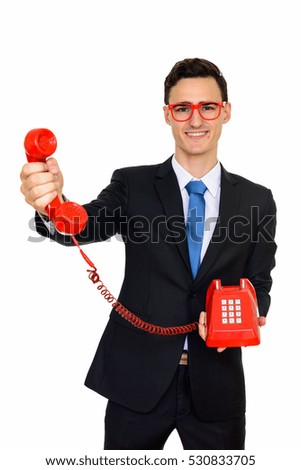 Studio shot of young happy Caucasian businessman giving phone isolated against white background