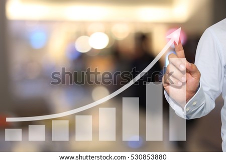 Businessman to touch in peak of Business graph on abstract blur background,Concept financial symbols coming success and profitability. Royalty-Free Stock Photo #530853880