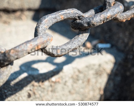 Picture of the selective focus on a rusty iron chain against the blurred background of the gray stones. Rusty iron chain close up.