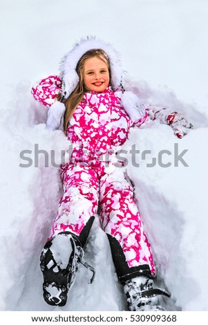The child, a girl lying in the snow and laughing. Merry Christmas for children.