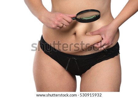 Fat overweight woman pinching her fat tummy under magnifying glass isolated on white background