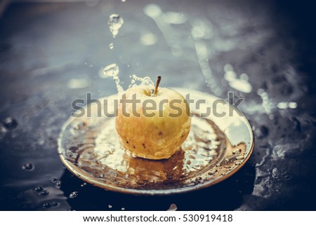 apples in the water stream with splashes standing on the plate outdoors