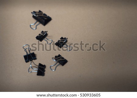 Black paper clips in row on brown plate
