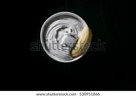 Banana with chocolate chip ice cream in bowl, top view, dark background and selective focus