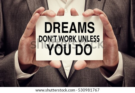 Dreams Don't Work Unless You Do. Motivational quote. Achievement concept written on a card in businessman hands