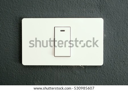 Electric switch at the gray painted wall