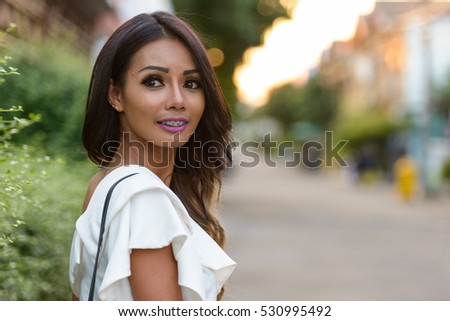 Portrait of beautiful young Asian woman with braces outdoors
