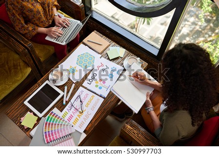 Female designers working on logo for the website, view from the top