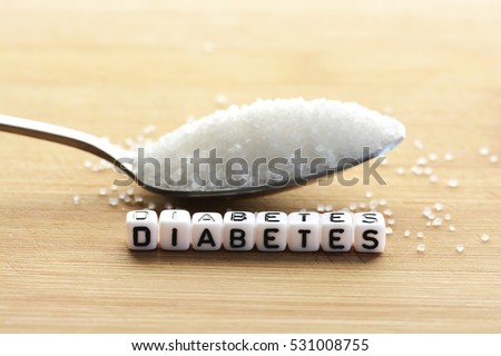 Diabetes block letters in crossword and sugar pile on a spoon  Royalty-Free Stock Photo #531008755