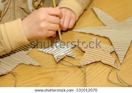 Children at a lesson of the fine arts, make gifts for a holiday of Christmas and new year. Cut out and do garlands of sheets of a cardboard. Preparation for a holiday.
