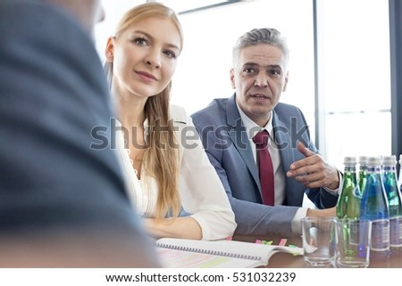Mature businessman discussing with colleagues at conference table in office