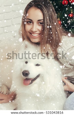 winter, christmas, animal, people, beauty concept- Young beautiful woman with husky dogs in a Christmas setting. over snow background