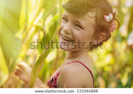 Five years old girl playing in a corn field.