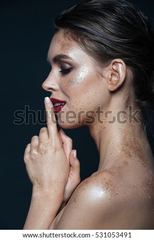 Profile of pretty young woman with sparkling makeup over black background
