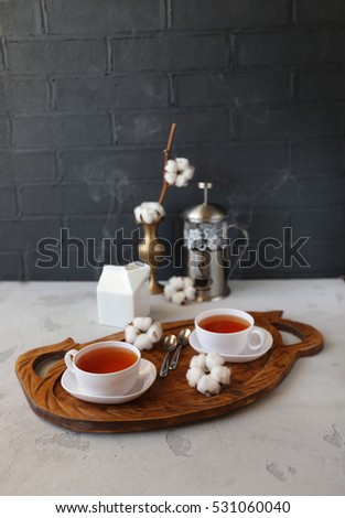 Two cups of hot tea and cotton flowers on rustic concrete background. Christmas or Valentine's  day celebration concept.