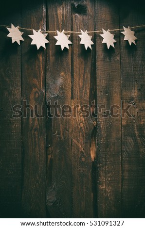 Simple Christmas cardboard stars garland decoration on dark barn wooden planks background. Empty space for copy, text lettering. Holiday postcard, greeting card, banner vertical template.