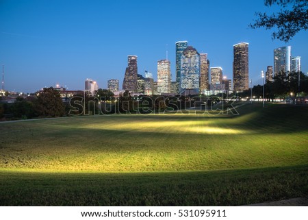 Downtown Houston illuminated at blue hour with green park lawn and modern skylines light. It is the most populous city in Texas and the fourth-most in United States. Architecture and travel background