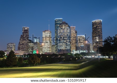 Downtown Houston illuminated at blue hour with green park lawn and modern skylines light. It is the most populous city in Texas and the fourth-most in United States. Architecture and travel background