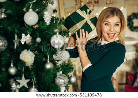 beautiful blonde holds in his hands a Christmas gift and smiling at camera