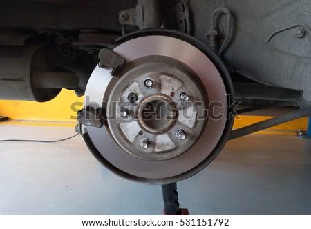 Close-up shot of a car's brake disc.Front disc brake on car in process of new tire replacement Braking system with disk open for repair maintenance and service Steel flywheel mounted on the engine  Royalty-Free Stock Photo #531151792