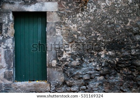 Green door on rock wall in Girona