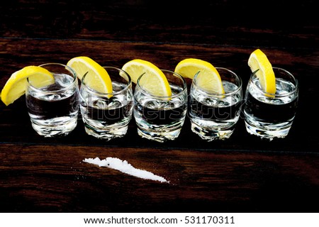 Tequila shots with lemons and salt  on the wooden table. Selective focus and small depth of field.