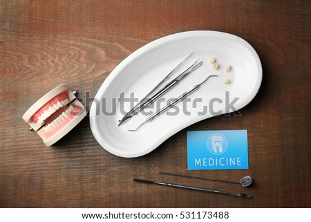 Business card and dental tools on wooden background. Medical service concept