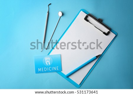 Business card, clipboard and dental tools on blue background. Medical service concept