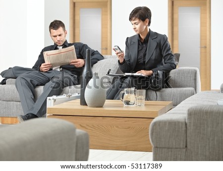 Business people sitting on sofa at office anteroom waiting.