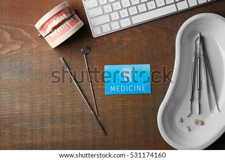 Business card, keyboard and dental tools on wooden background. Medical service concept