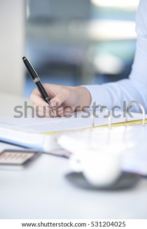 Close-up shot of a young businesswoman sitting at desk and sign the contract.