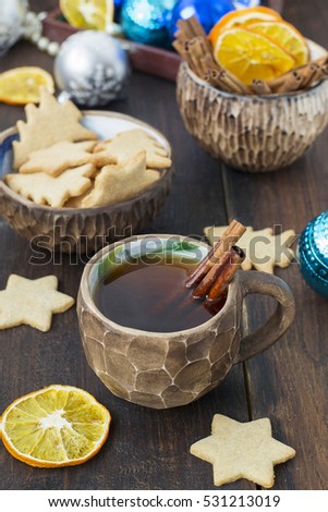 Tea with spices in a clay cup of ginger biscuits and Christmas decorations.
